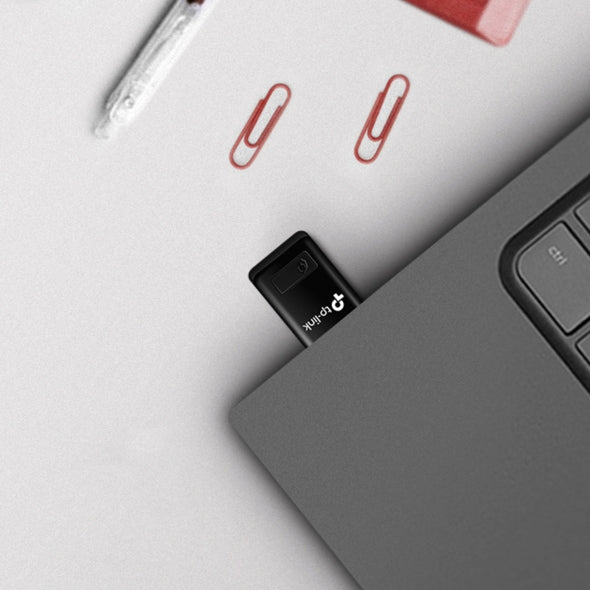 USB drive inserted into a laptop with paper clips on a grey surface